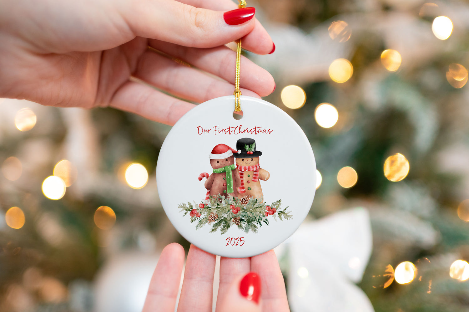 UV printed ceramic ornament featuring a gingerbread couple with greenery, candy canes, and “Our First Christmas 2025” text, held in front of a Christmas tree with lights.