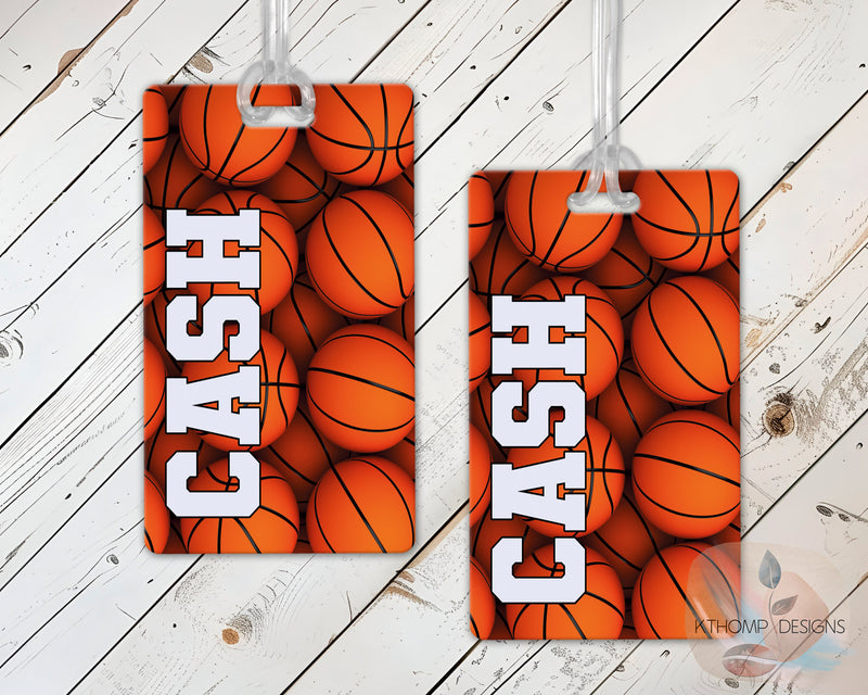 Two sports bag tags with basketball design with name and number on a wooden surface.