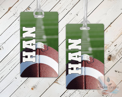 Two sports bag tags with football design with name and number on a wooden table