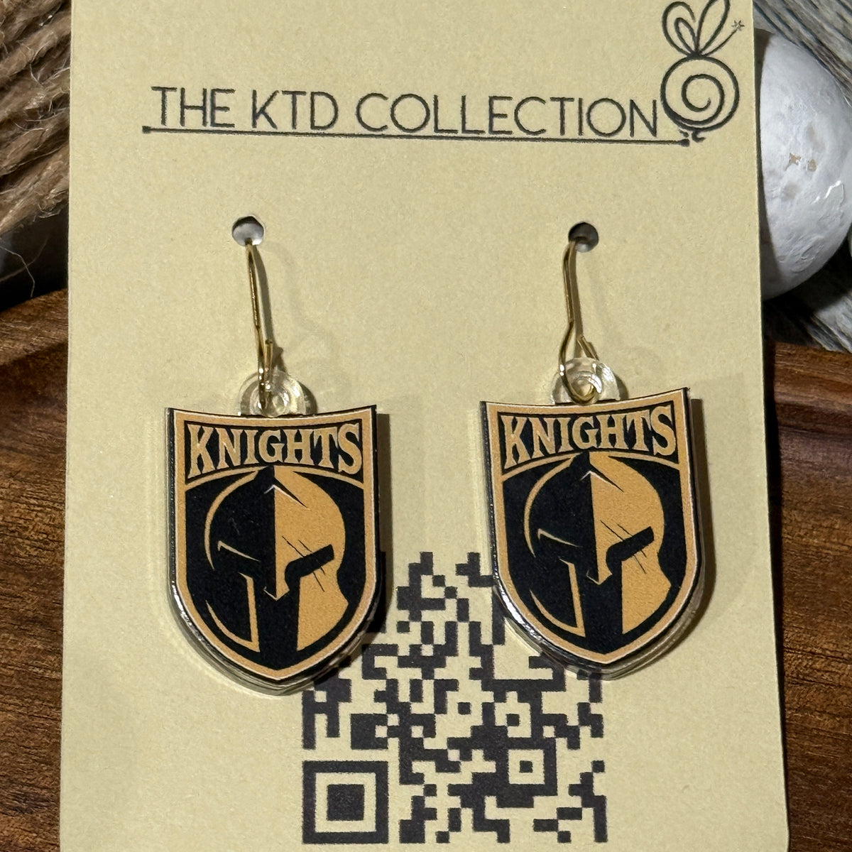 UV printed dangle earrings featuring the Canandaigua Knights logo on clear acrylic, hanging on gold hooks and displayed on The KTD Collection earring card