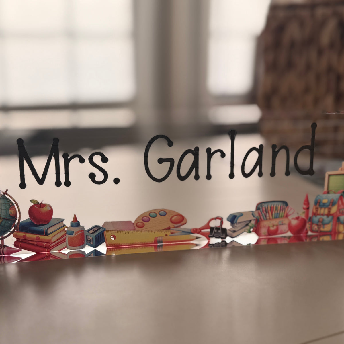 Decorative acrylic block with educational-themed items and teacher text on a desk
