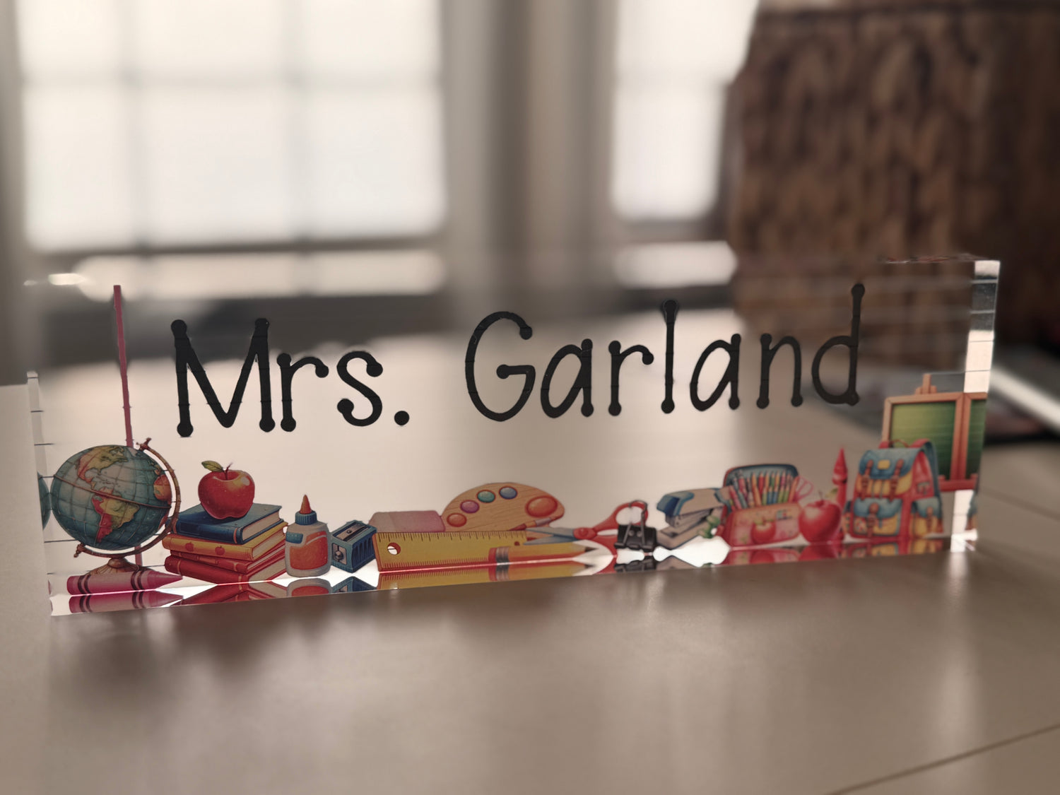 Decorative acrylic block with educational-themed items and teacher text on a desk