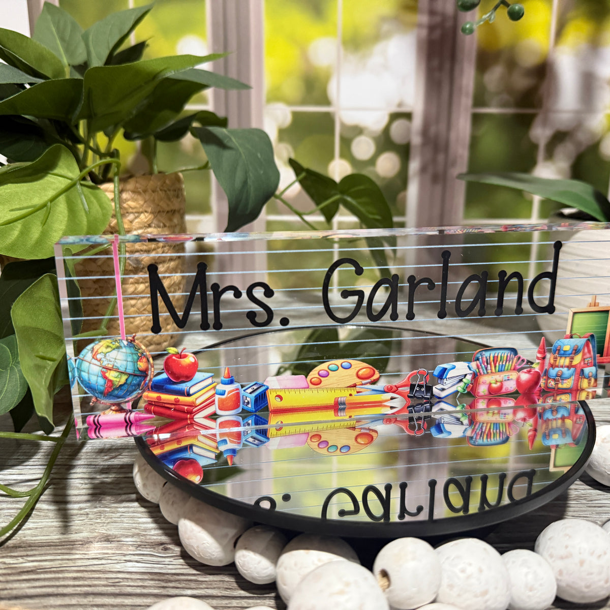 Personalized acrylic teacher desk name block with floral background and elegant script font, placed on a wooden desk