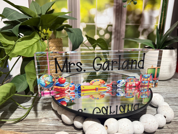 Personalized acrylic teacher desk name block with floral background and elegant script font, placed on a wooden desk