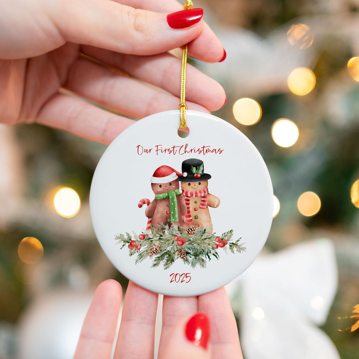 UV printed ceramic ornament featuring a gingerbread couple with greenery, candy canes, and “Our First Christmas 2025” text, held in front of a Christmas tree with lights.